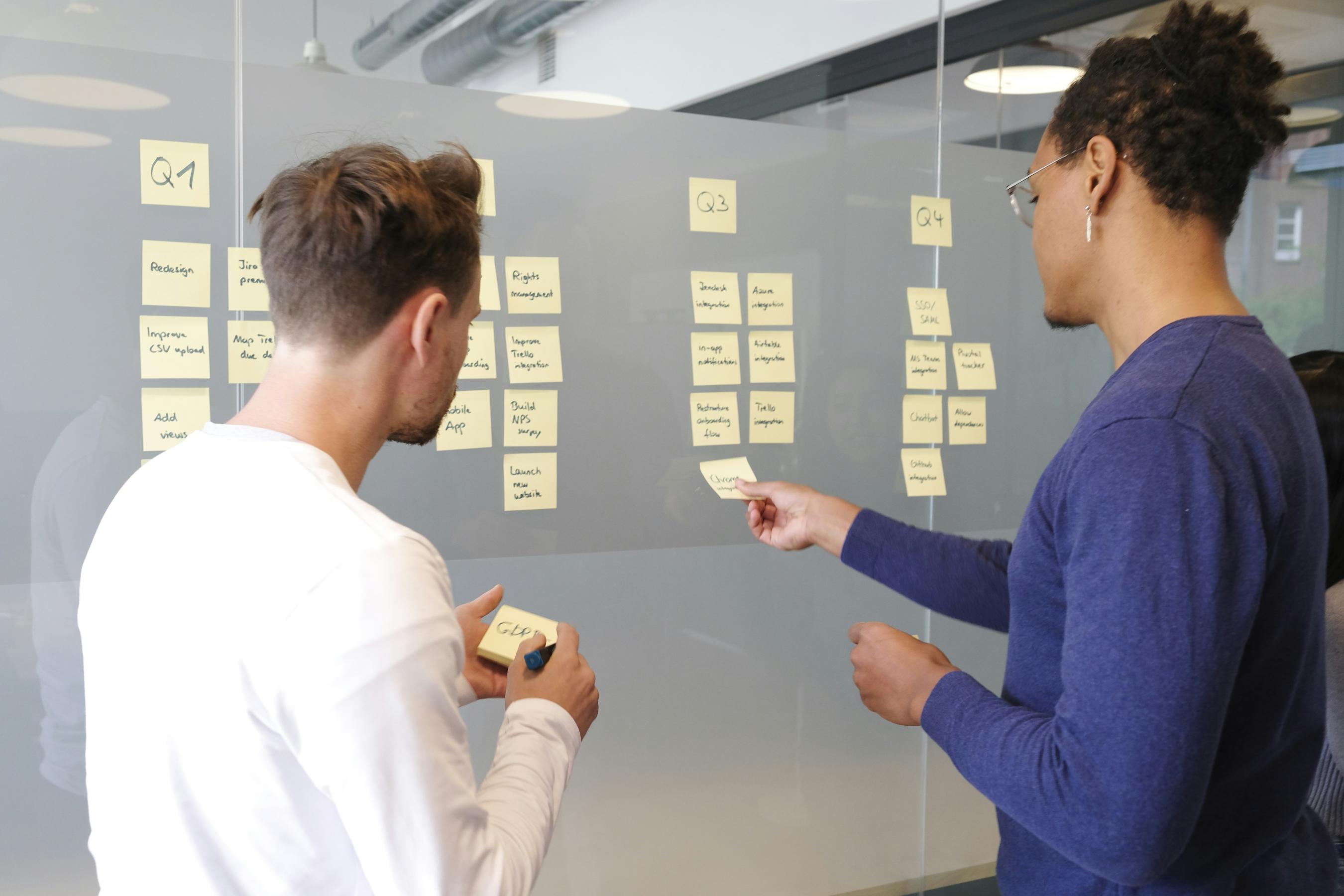 two men discussing product lifecycle with post-its on board