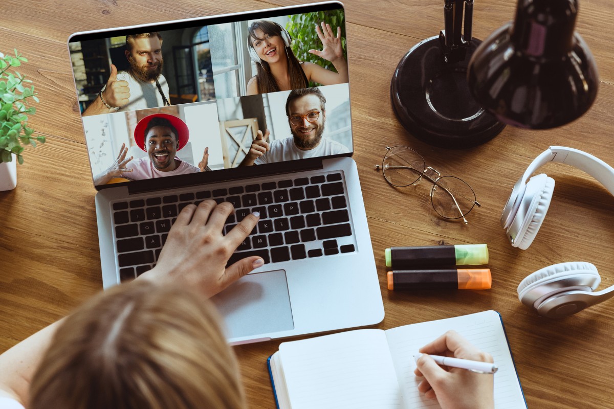 A person using a computer with people on the screen undertaking a video call